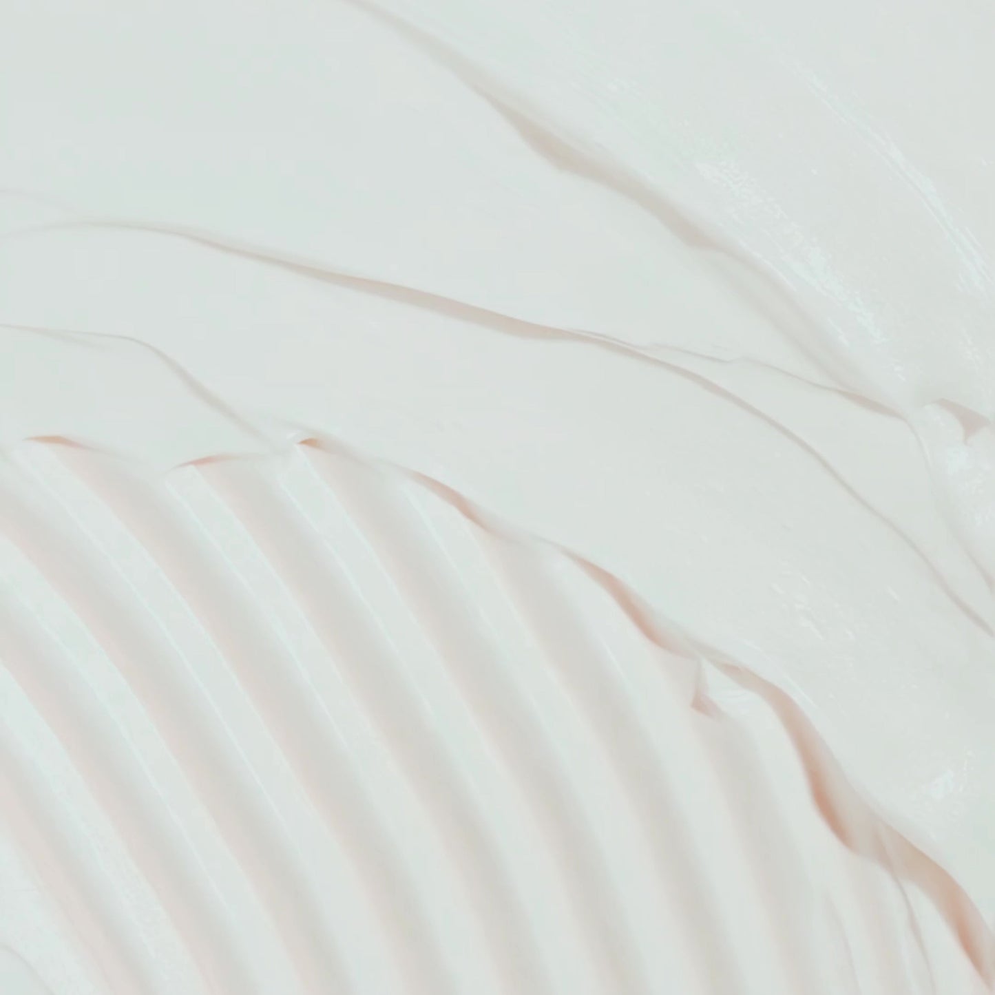 The image is a close-up of a white, wavy substance, possibly cream or lotion, with a textured, ribbed appearance.