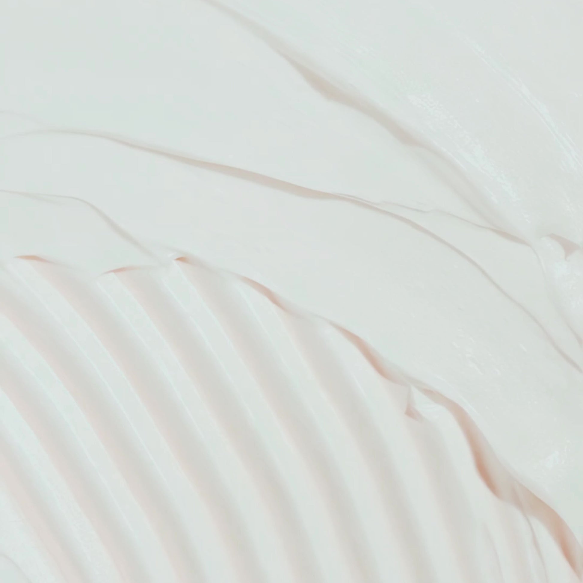 The image is a close-up of a white, wavy substance, possibly cream or lotion, with a textured, ribbed appearance.