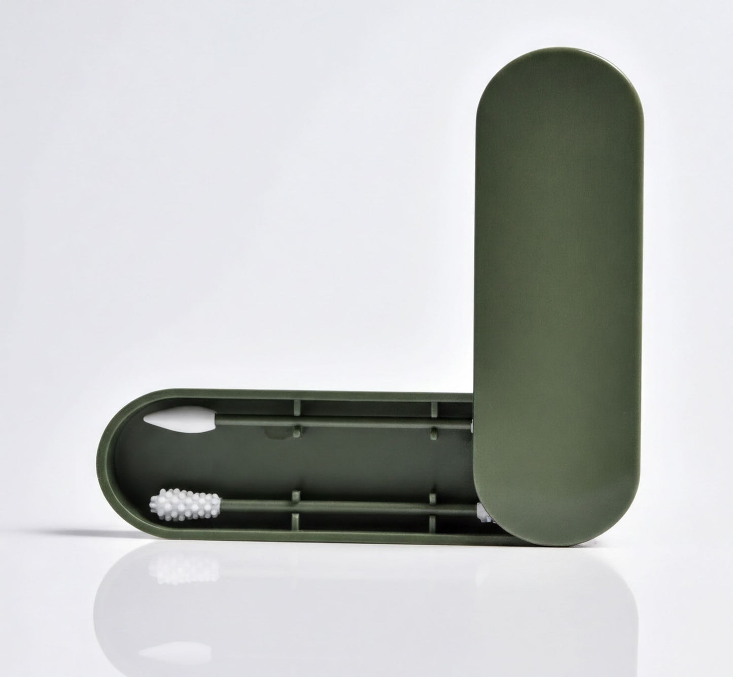 a green plastic container with a white cotton swab inside, placed on a white surface.