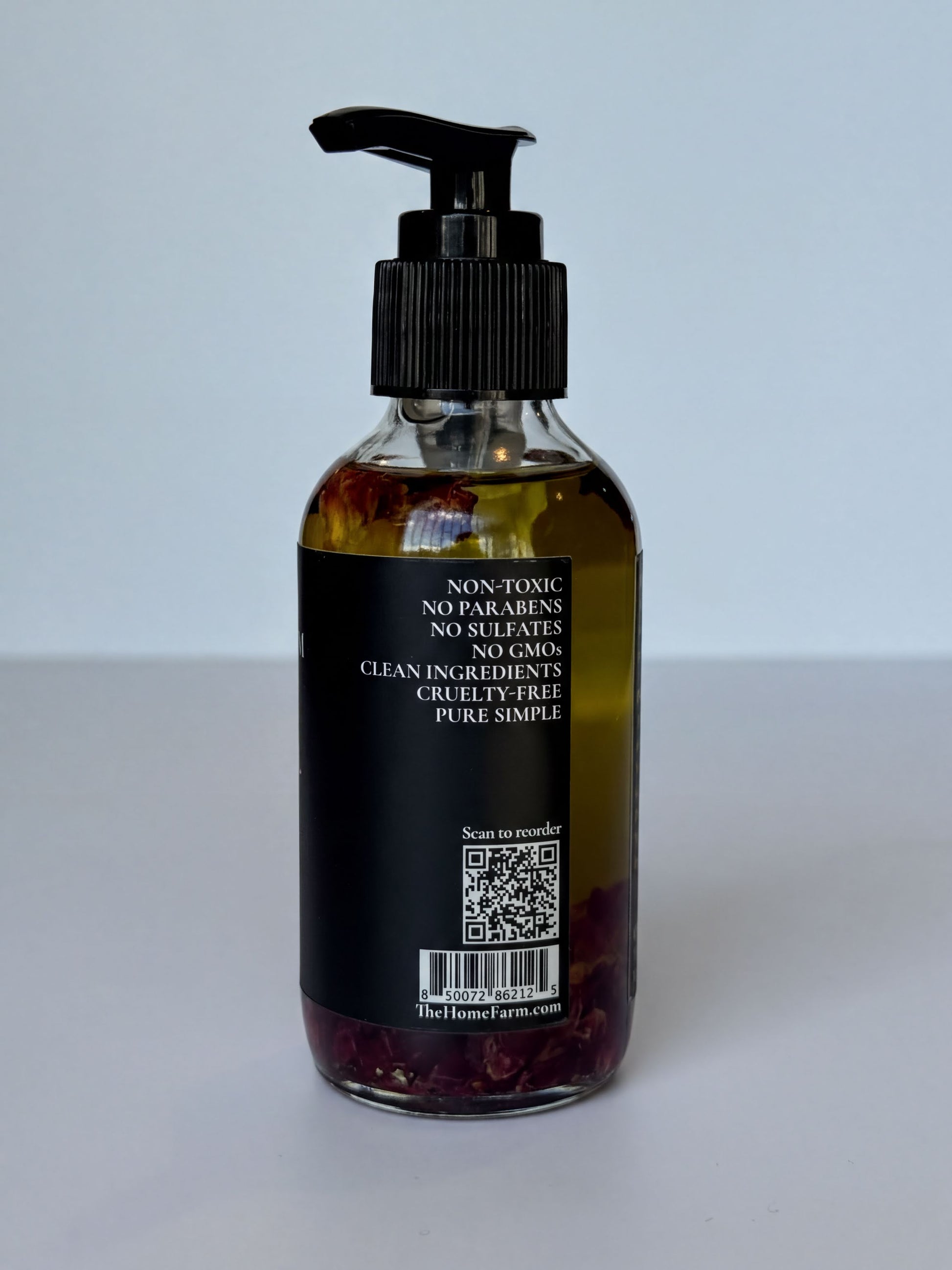 a bottle of liquid with a pump dispenser, containing a yellowish liquid and red or purple flowers. The label on the bottle provides information about the product, including that it is non-toxic, contains no sulfates, and is made from clean ingredients.