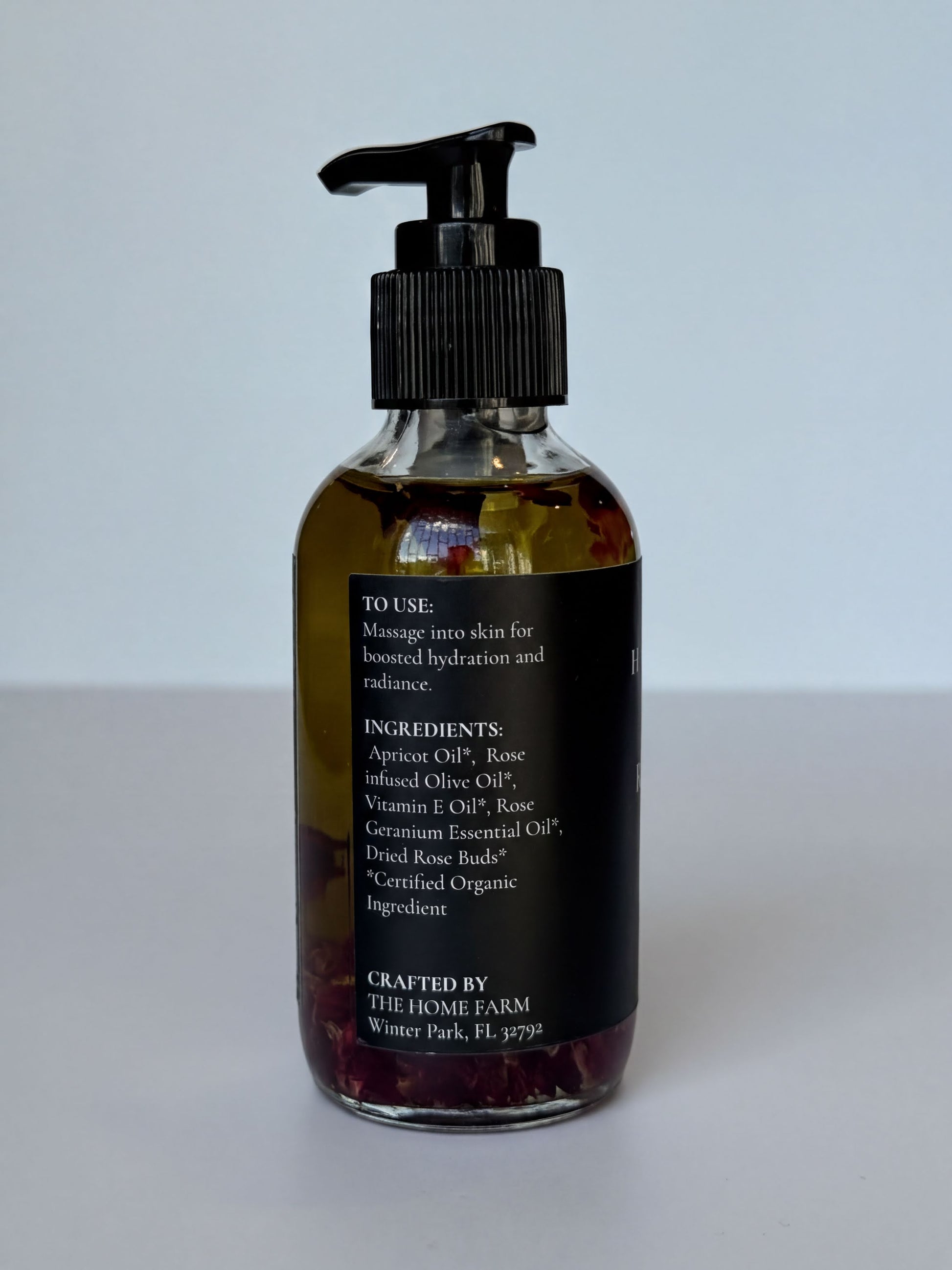 A bottle of essential oil with a pump dispenser, containing a mixture of rose oil and other ingredients.