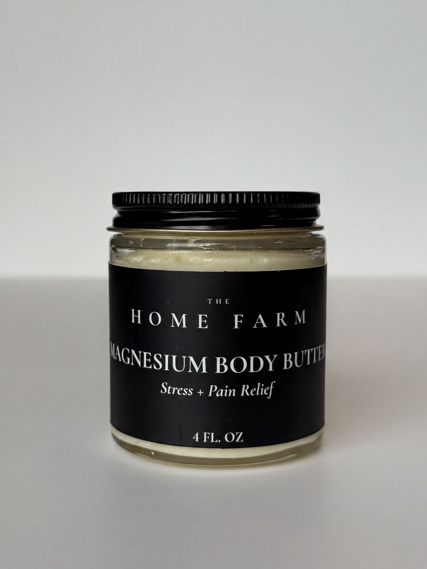 A jar of magnesium body butter with a black lid, labeled as a stress and pain relief product.