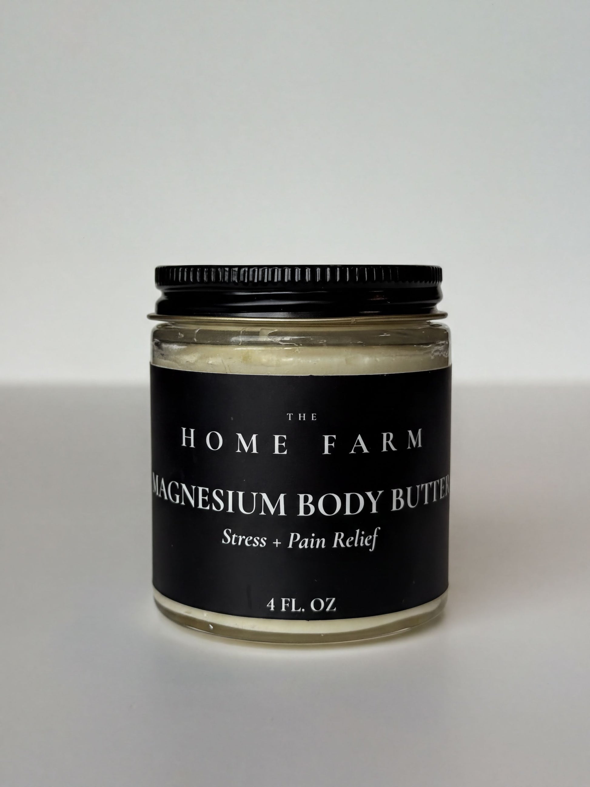 A jar of magnesium body butter with a black lid, labeled as a stress and pain relief product.