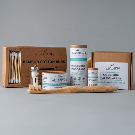 a collection of natural beauty products, including a bamboo toothbrush, a face balm, a deodorant, and a face cleansing bar, all packaged in cardboard boxes.
