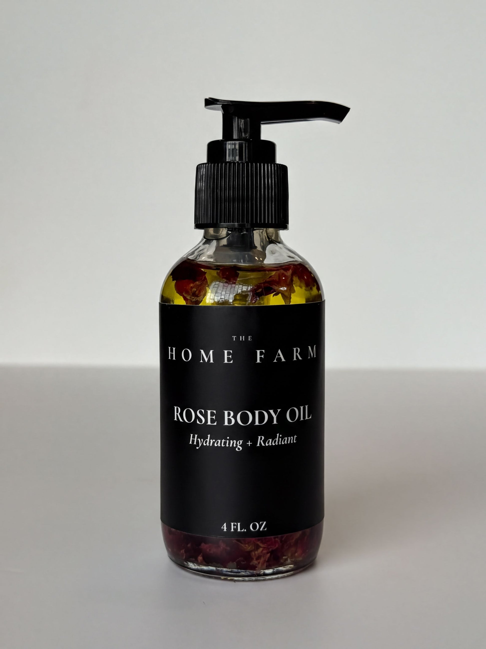 A bottle of rose body oil with a pump dispenser, containing rose petals and oil.