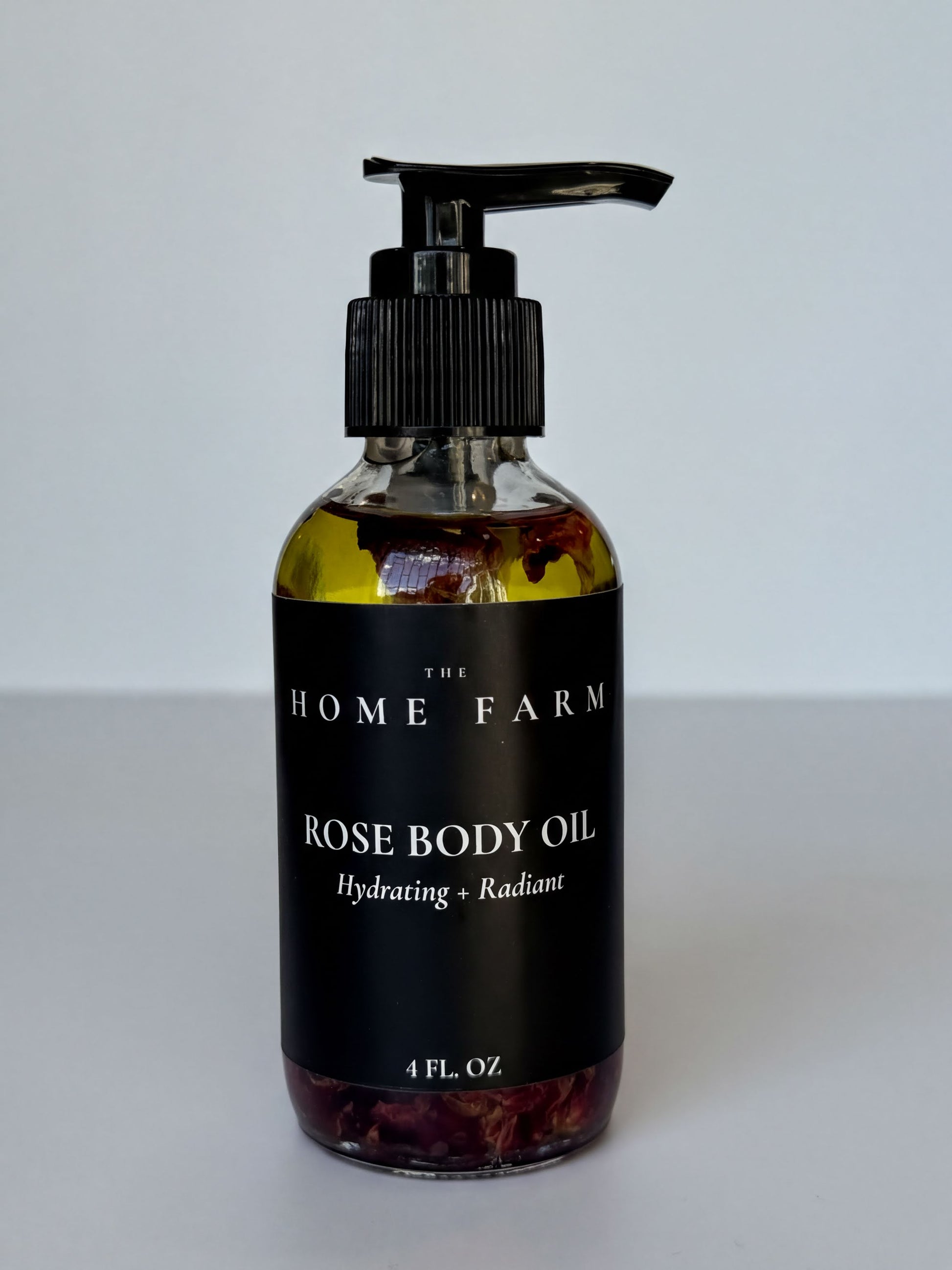 A bottle of rose body oil with a pump dispenser, labeled as a hydrating and radiant product.