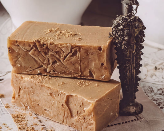 two rectangular bars of brown soap placed on a table, with a decorative metal object next to them.