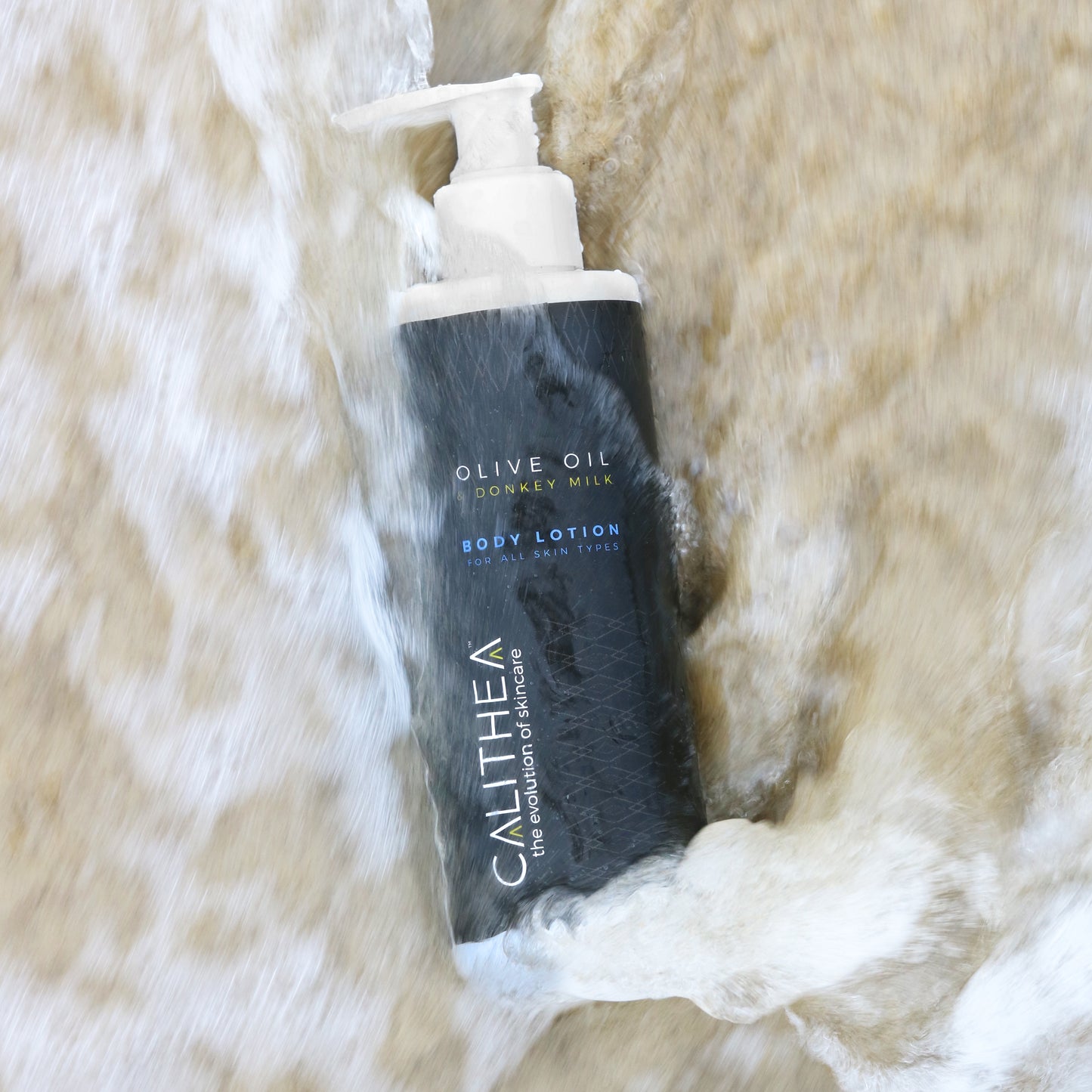 A bottle of body lotion with a pump dispenser, placed on a surface with water splashing around it.