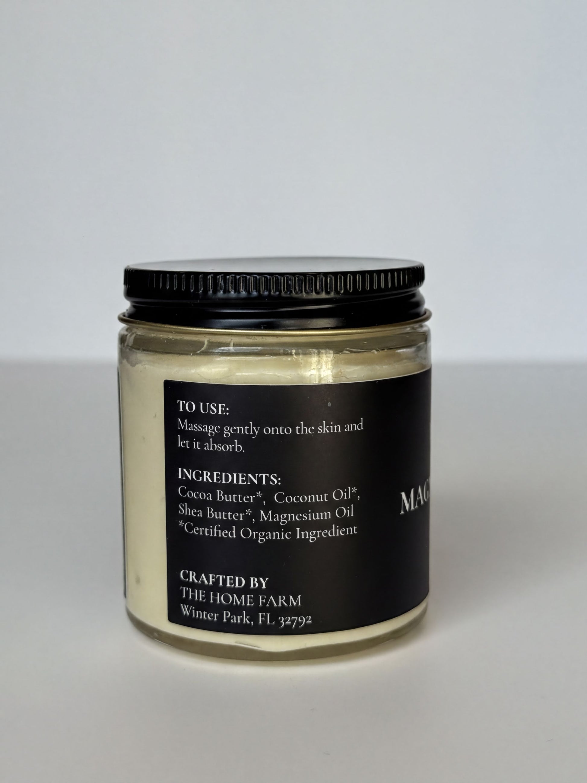 A jar of magnesium oil with a black lid, sitting on a white surface.